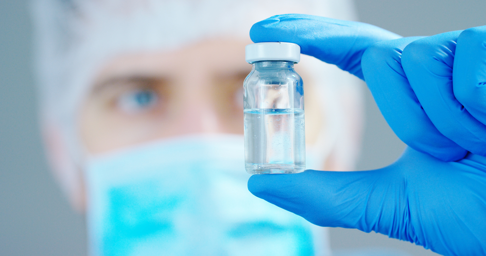 A scientist in laboratory holding a syringe with liquid vaccine.