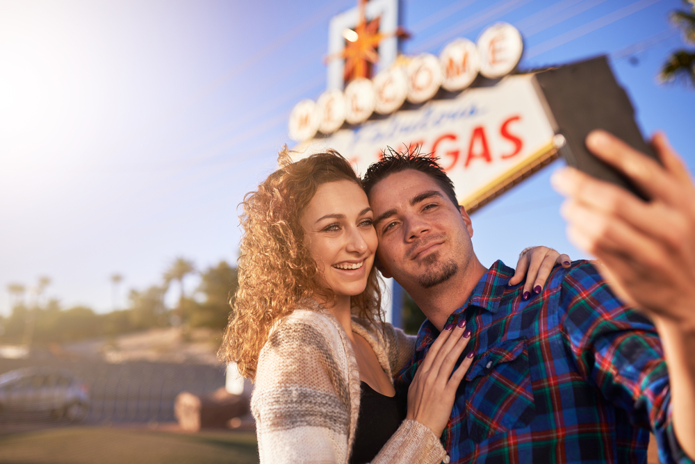 2 tourists taking a picture in front of famous "Welcome to Las Vegas" sign