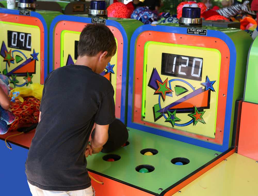 boy plays whac a mole carnival game