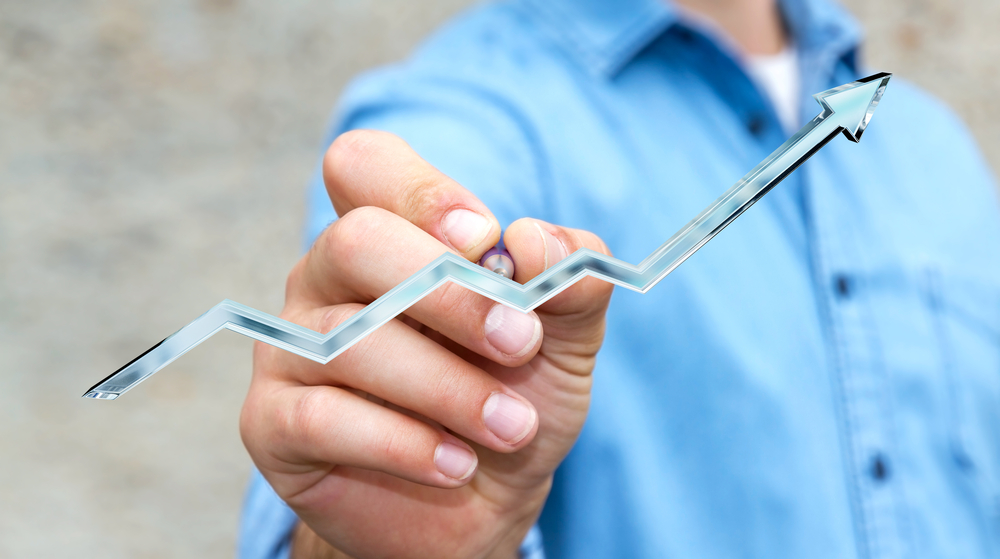 Businessman on blurred background drawing ascending digital blue arrow