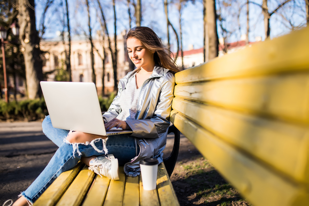 girl using laptop on bench