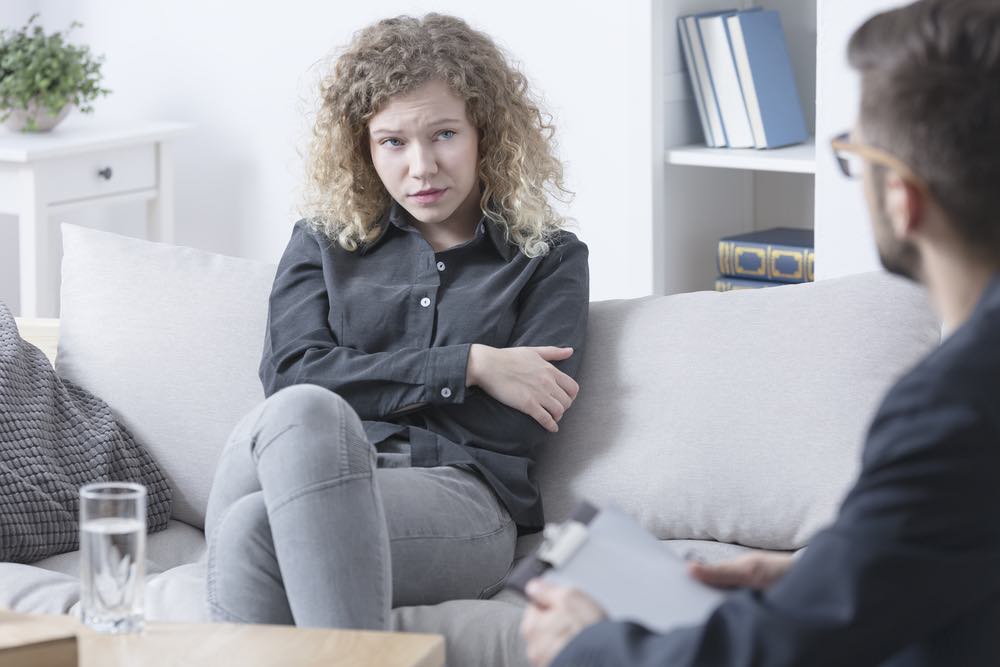 A woman sits on a couch talking to a therapist.