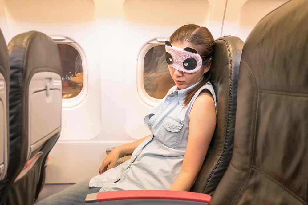 Woman sleeping with eye mask on plane