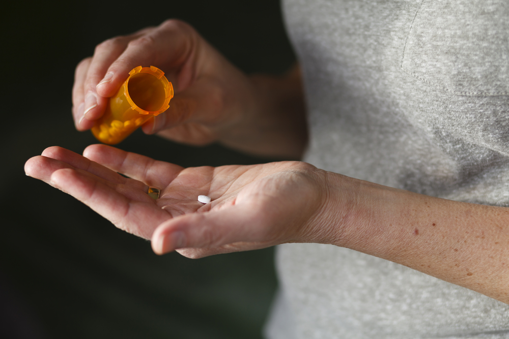 Close up of a woman's hands taking a pill from a bottle.