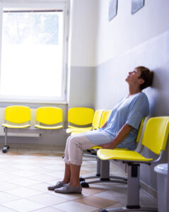 A woman sitting in a waiting room, head against the wall.