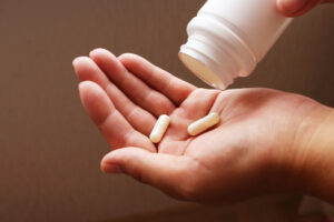 young woman pours the pills out of the bottle and into her hand.