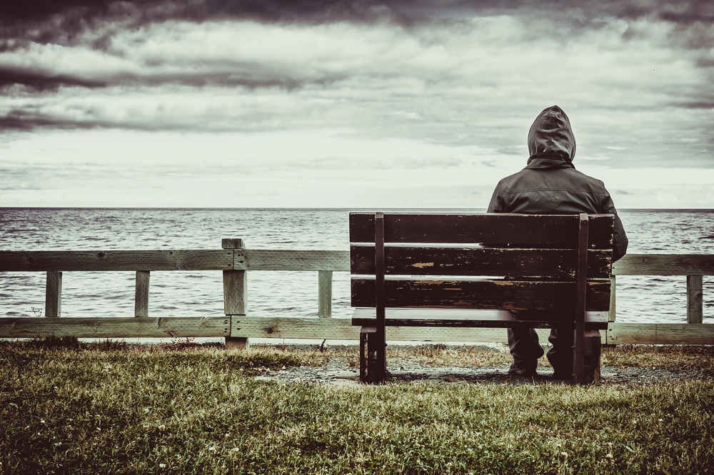 Man sitting on bench looking at sea