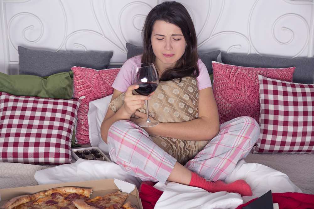 A woman eating pizza holding a glass of wine