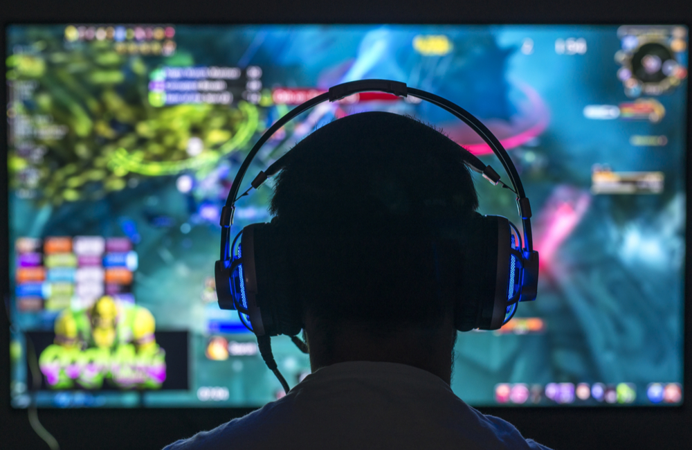 Man's head silhouetted against a colorful computer screen.