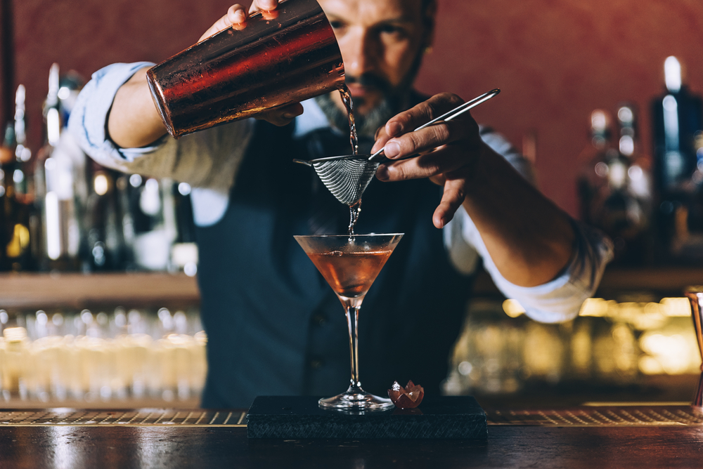 Expert barman is making cocktail at night club.