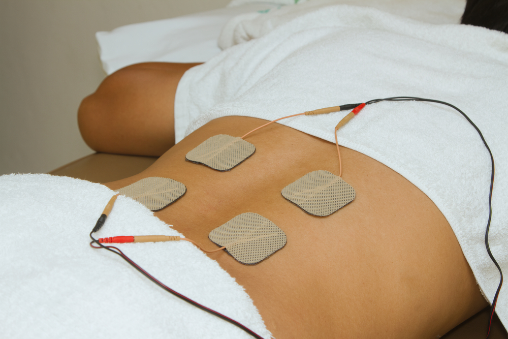 Patient with electrical stimulation therapy ( TENS ) on his back