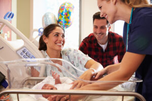 Family and nurse with newborn baby in maternity ward