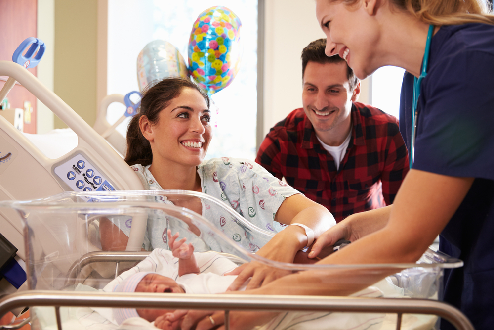 Family and nurse with newborn baby in maternity ward