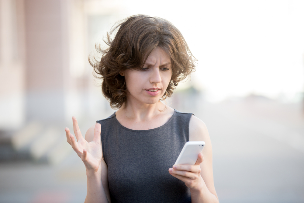 Woman looks frustrated with her phone.