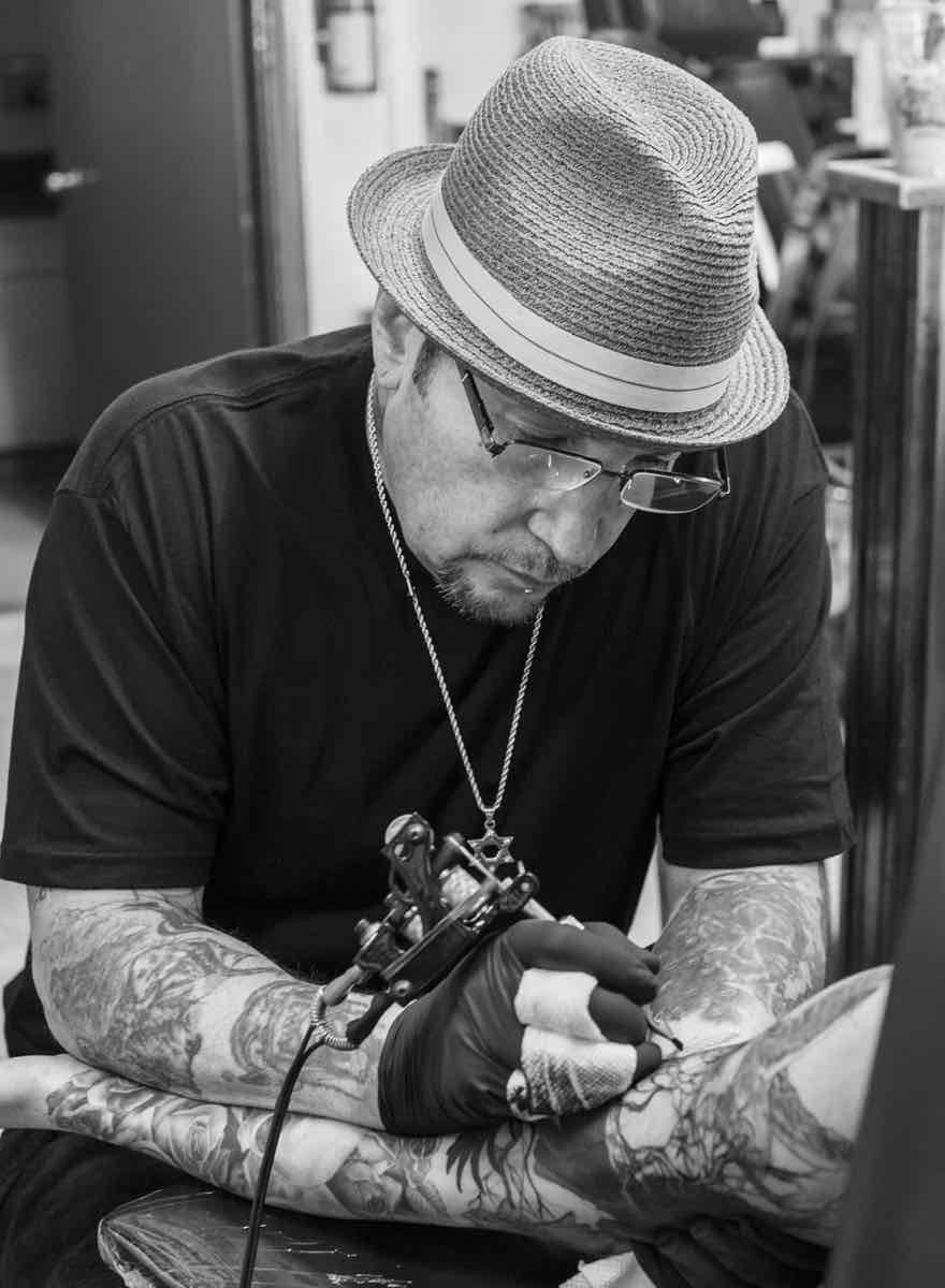Freddy Negrete tattooing an arm.