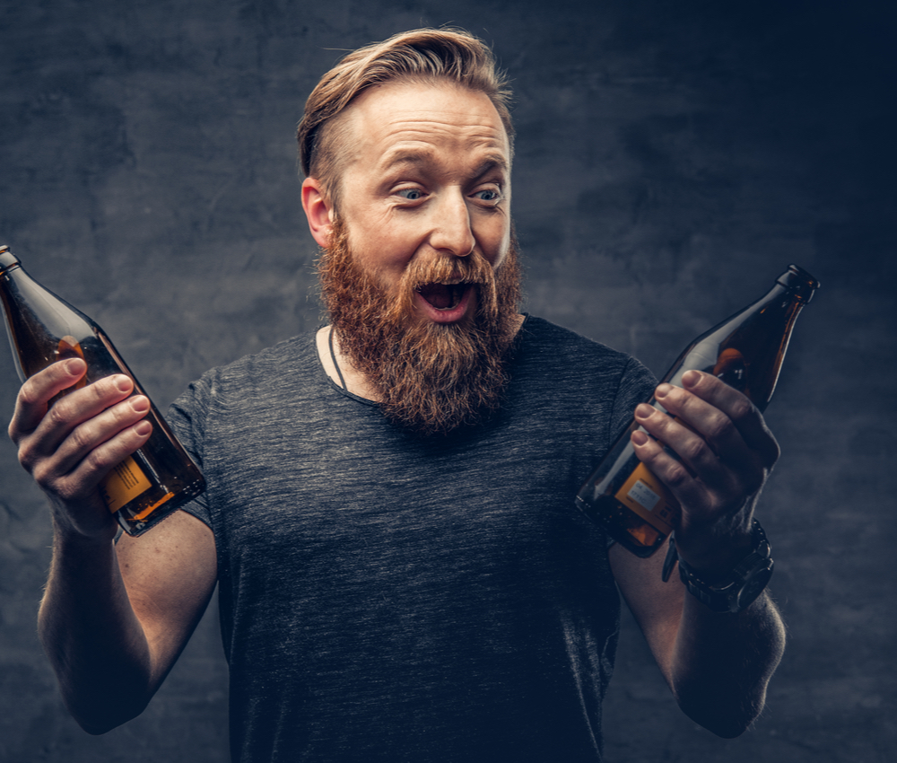 An excited man holding two beer bottles
