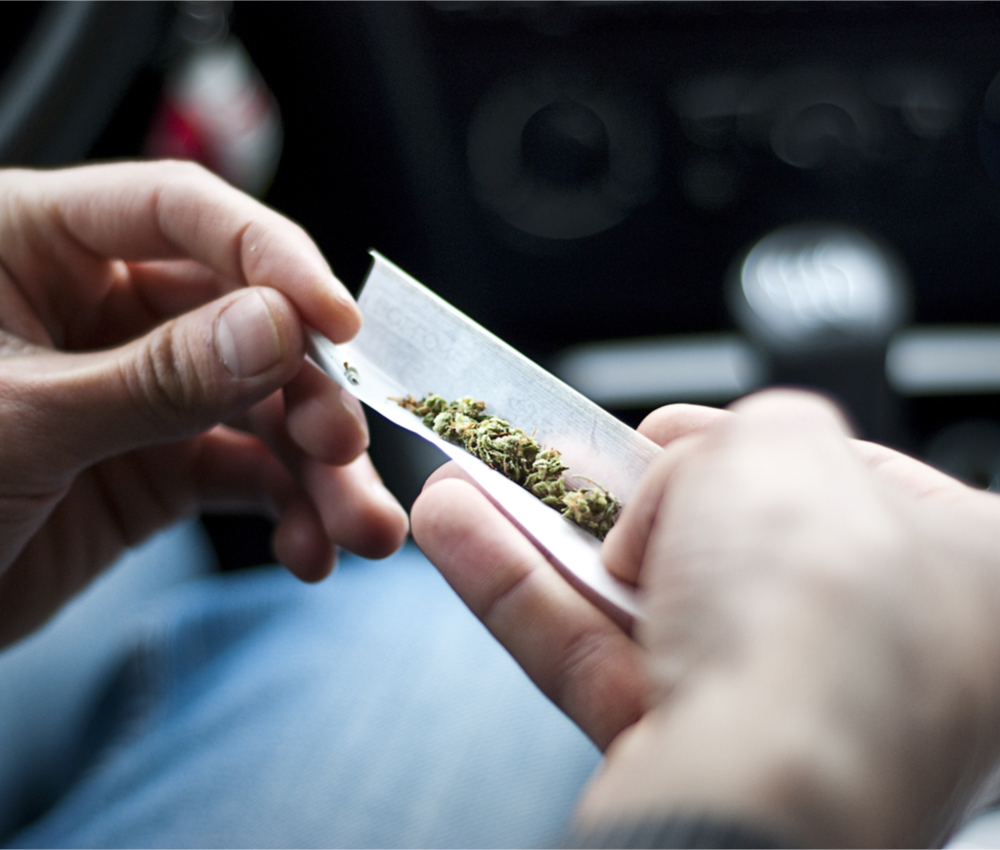 person rolling joint in car