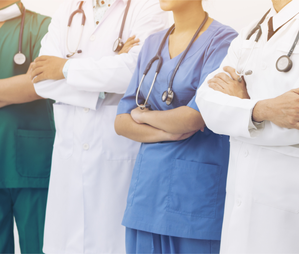 four medical professionals standing with their arms crossed