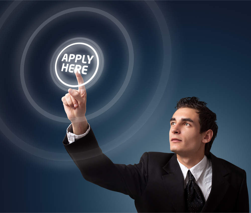 man in suit pushing apply here button