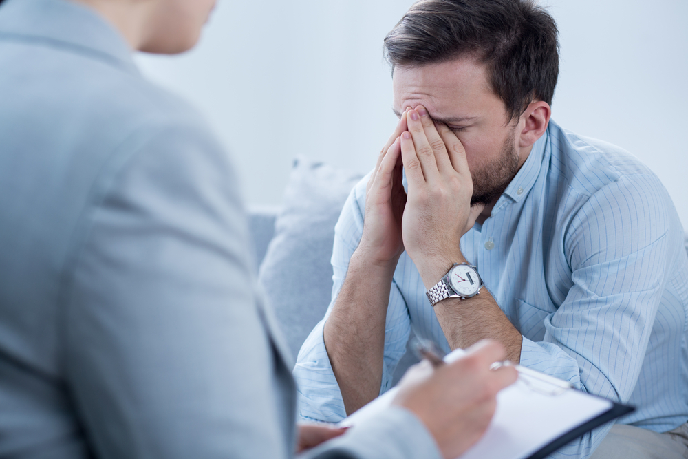 emotional man sitting on couch during therapy session.