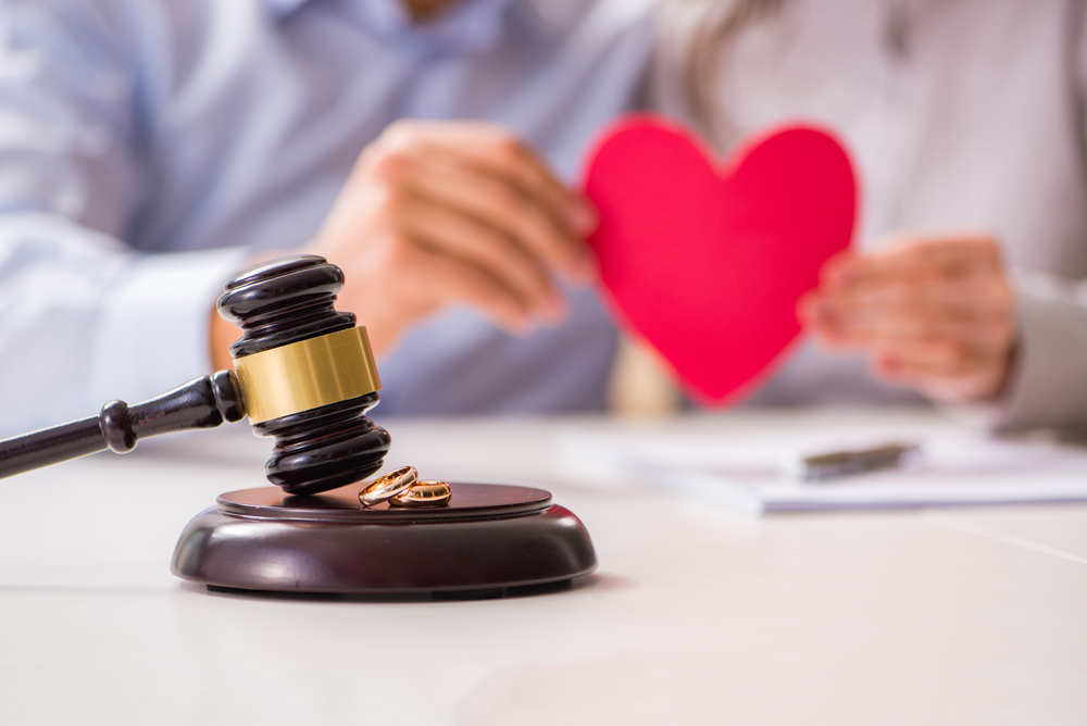 Couple holding a red paper heart with a gavel in the foreground.