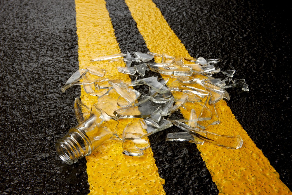 Close up of shattered alcohol bottle on road.