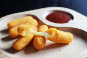 Cheese sticks served on a plate with sauce with good presentation.