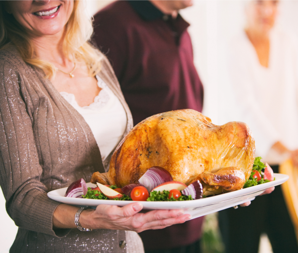 woman holding a giant turkey on a platter.