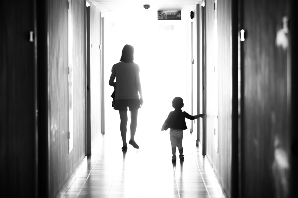 Black and white photo of mother and young daughter walking away