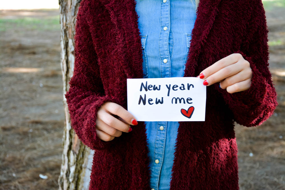 Woman's hands holding a note with new year new me text