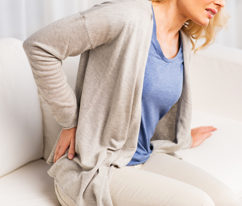 woman clutching her lower pain in back
