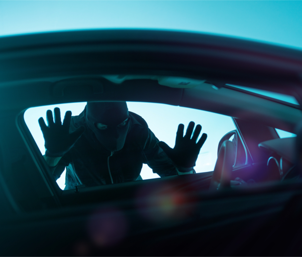 car thief looking through driver's side window of car.