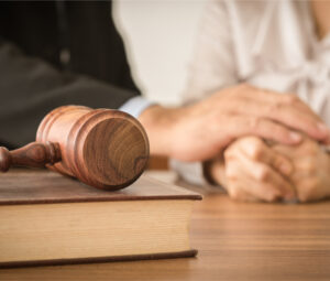 Judge gavel, man and woman in background consoling each other