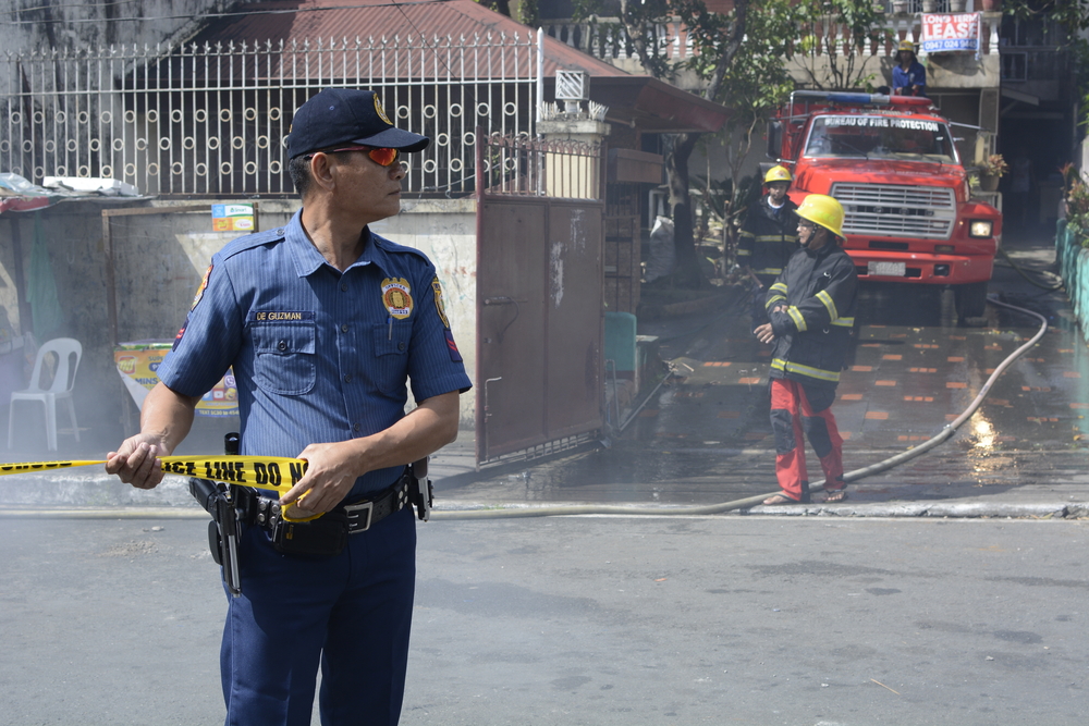 SAN PABLO CITY, LAGUNA, PHILIPPINES - MARCH 7, 2017: Police officer help maintain order during house fire that gutted interior shanty houses