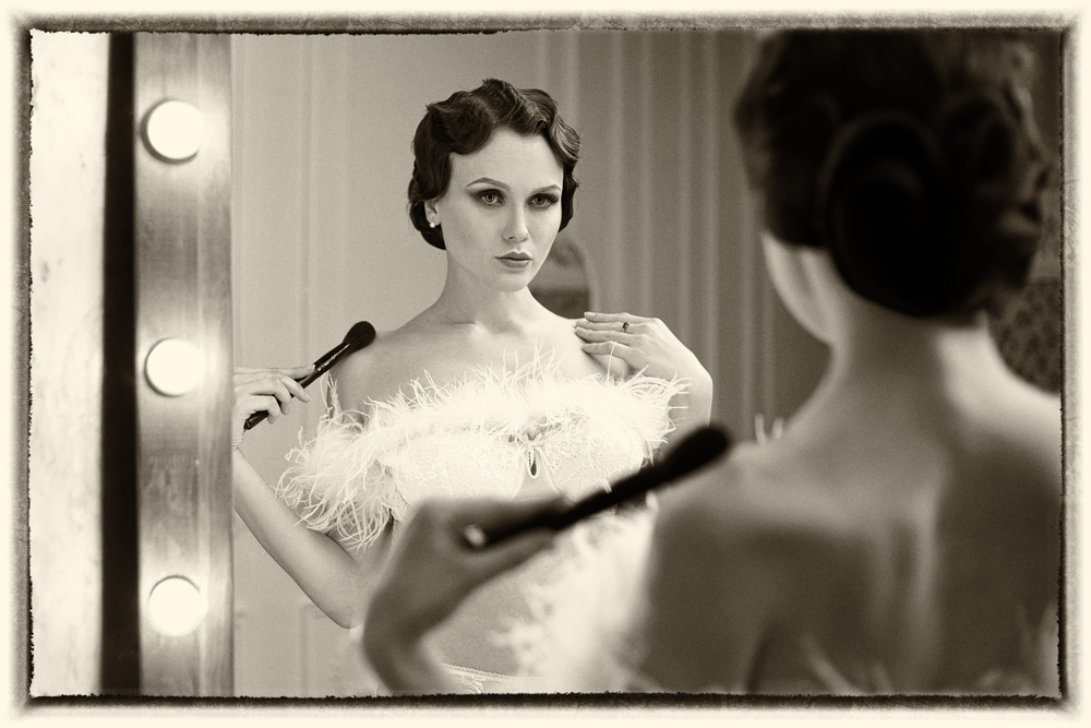 A vintage image of a woman in flapper clothing looking at herself in a mirror