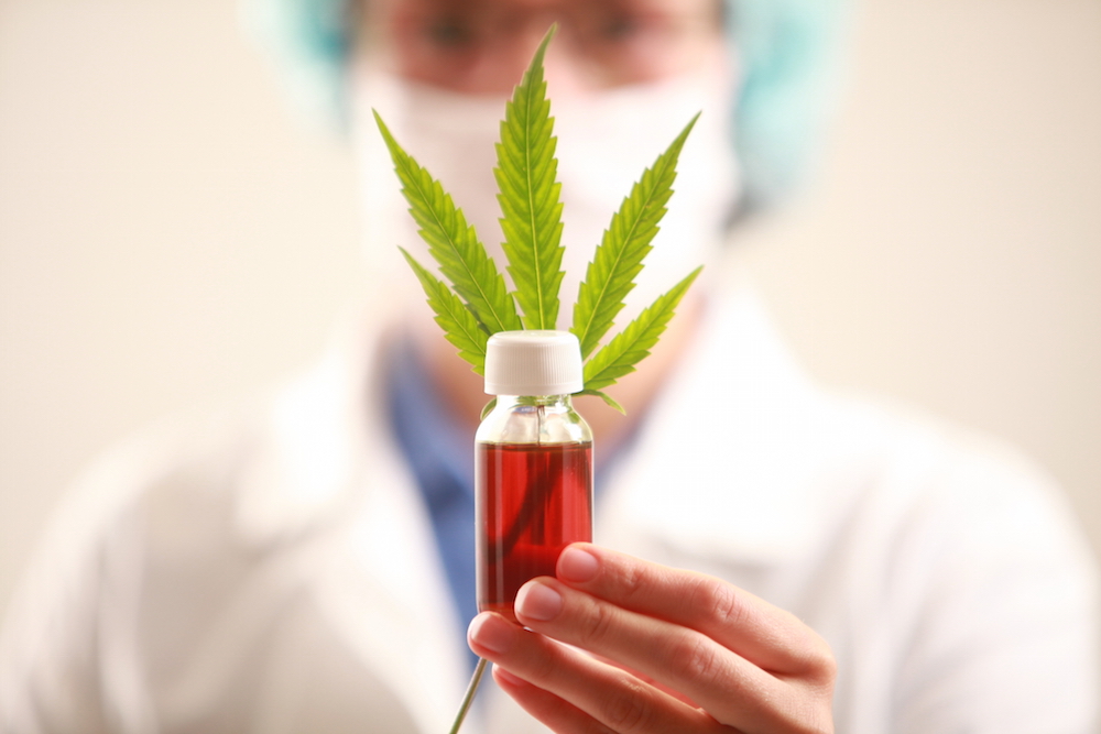 doctor holding a cannabis leaf and oil.
