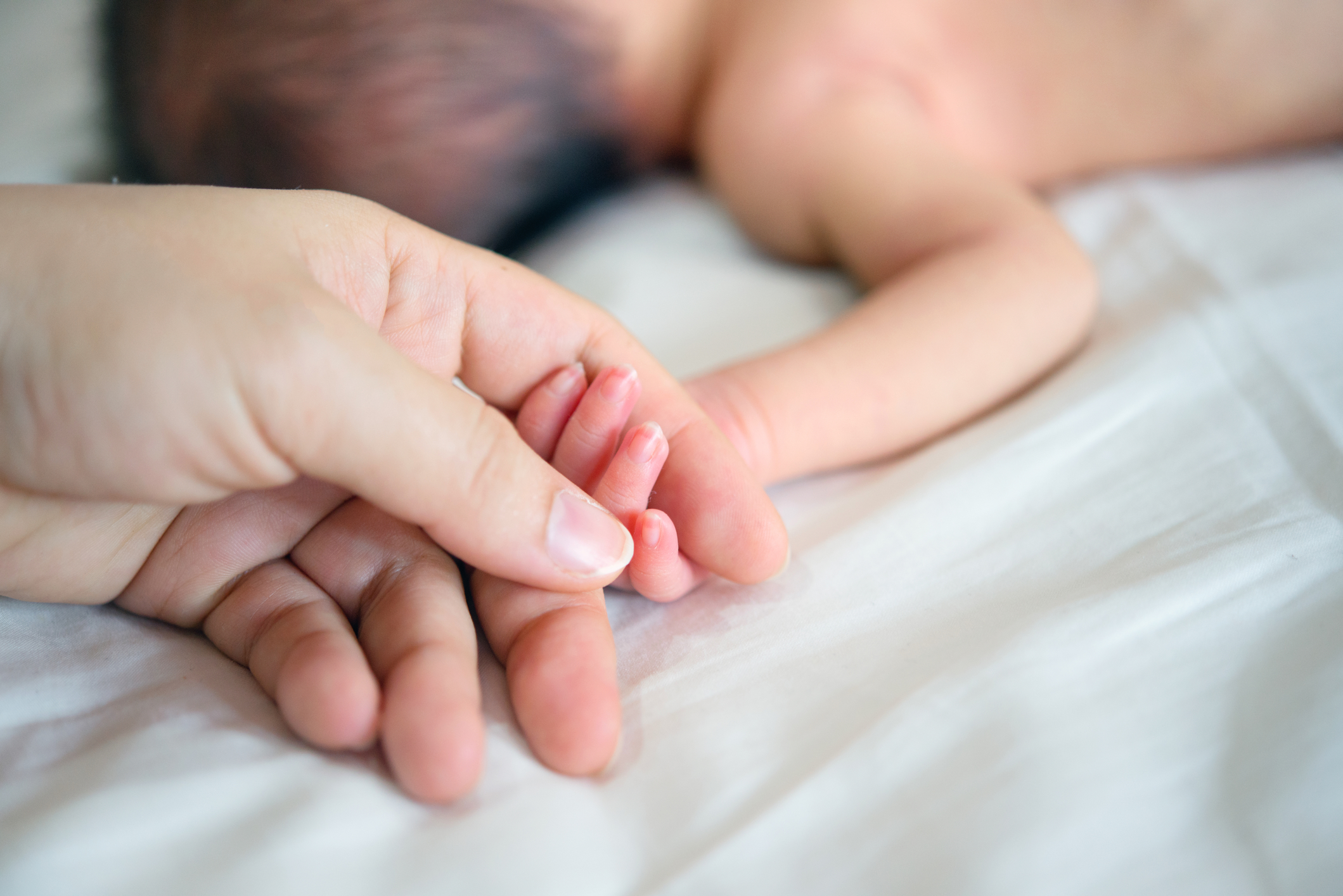 Sleeping newborn baby in the hand of mother close-up.