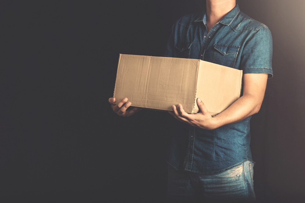 man holding a box against a dark background