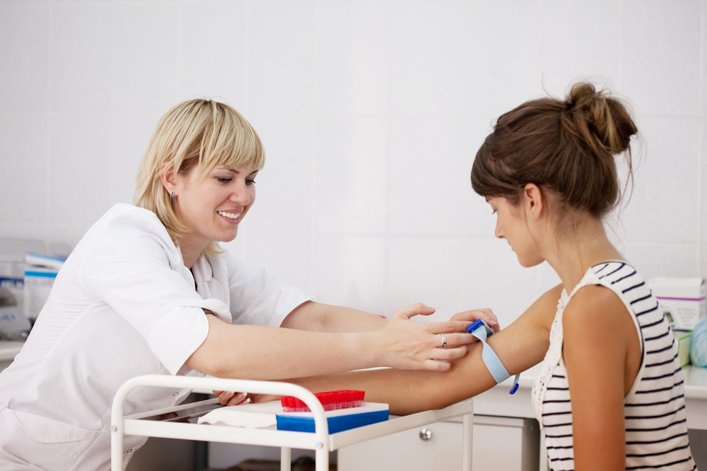 Nurse taking blood sample from patient in clinic