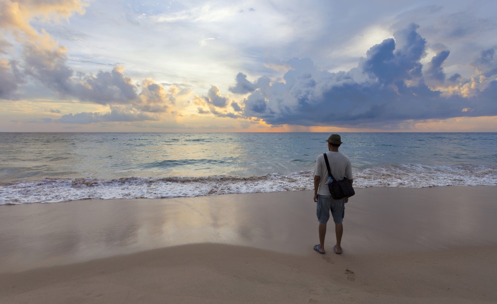 man on beach looking at sunrise