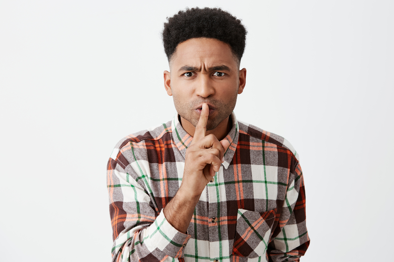 Man holding finger at mouth indicating "shh."