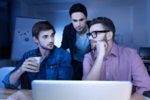 Group of college-aged men pondering near a laptop