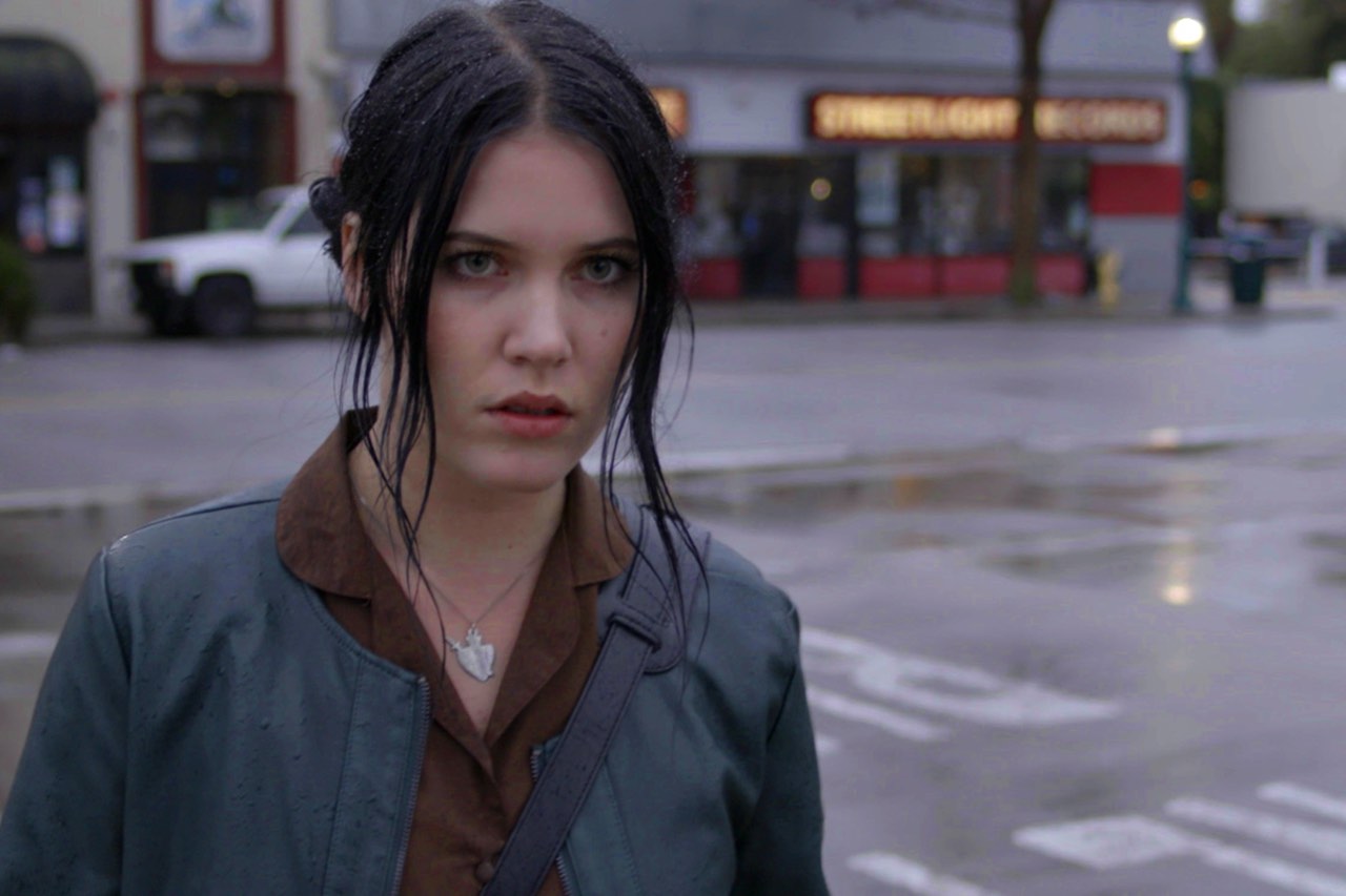 A woman standing in the street, looking concerned.