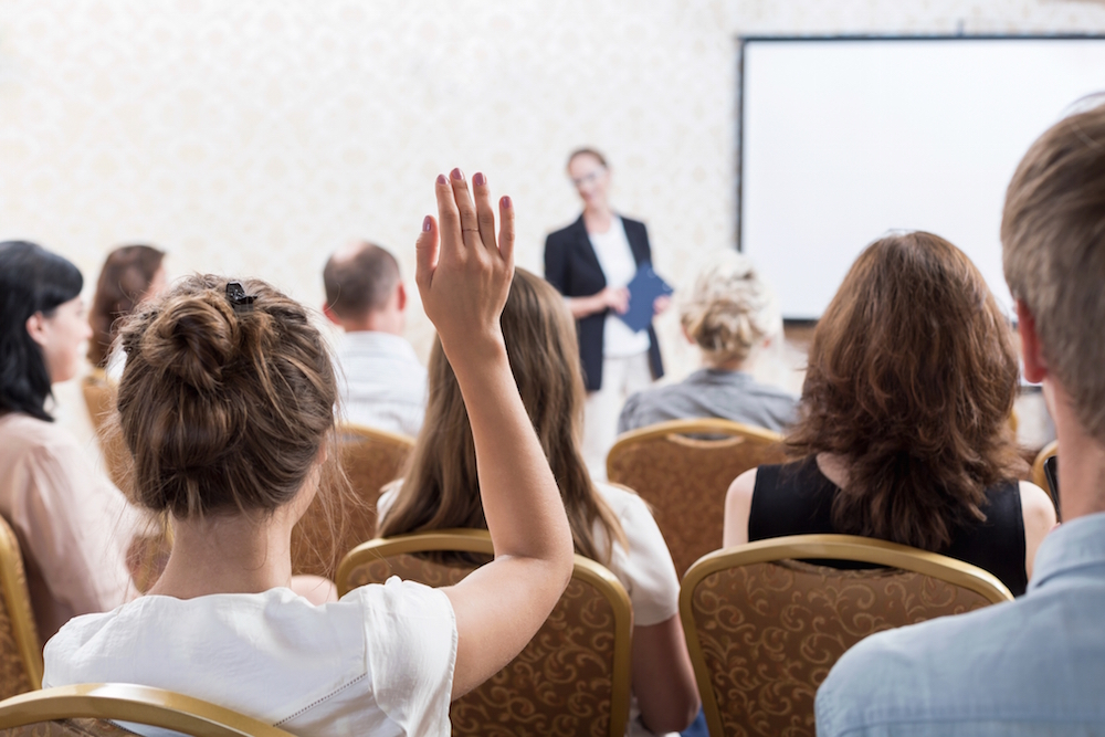 woman in audience raising hand