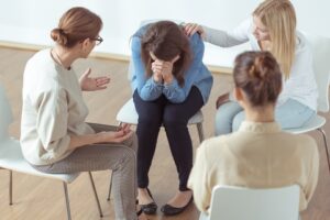 A group of four women in therapy, one is crying.