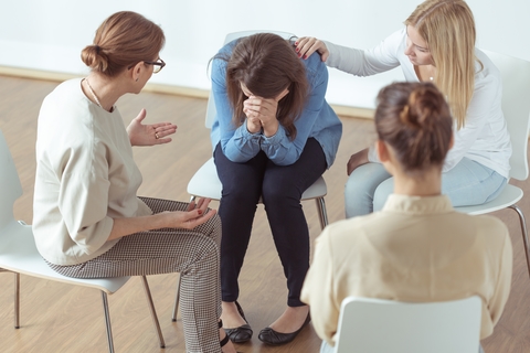 A group of four women in therapy, one is crying.