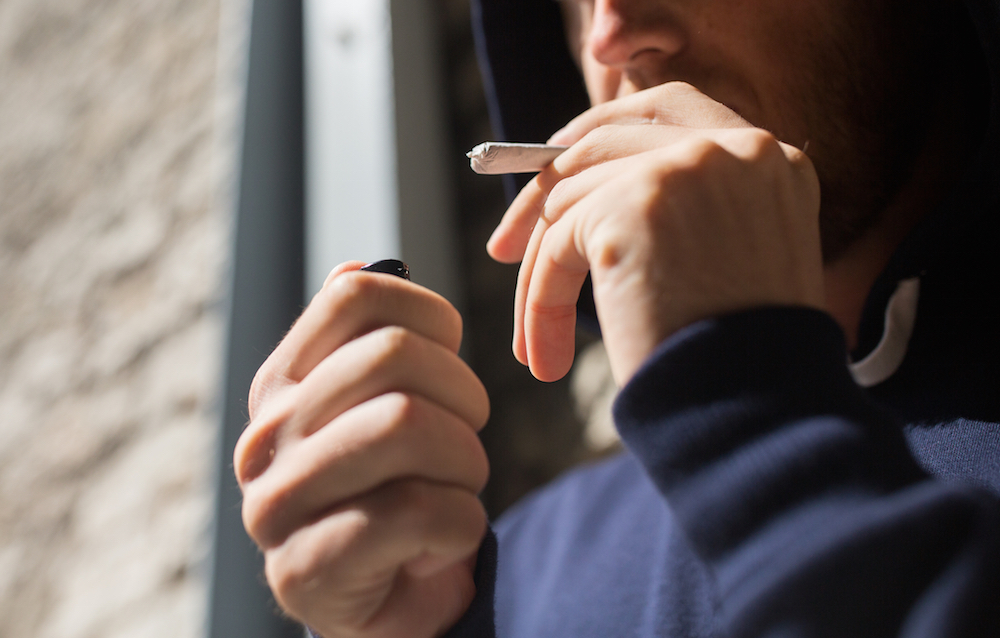 man in the process of lighting a joint