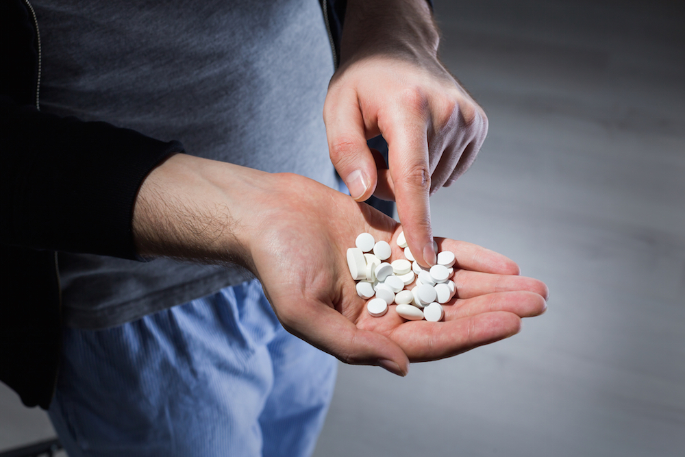 man counting white pills