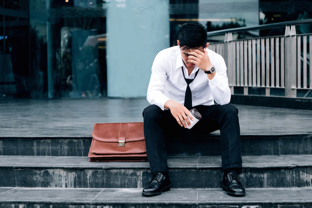 Unemployed, stressed businessman sitting on the walkway