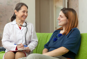 Friendly doctor and patient sitting together on couch.